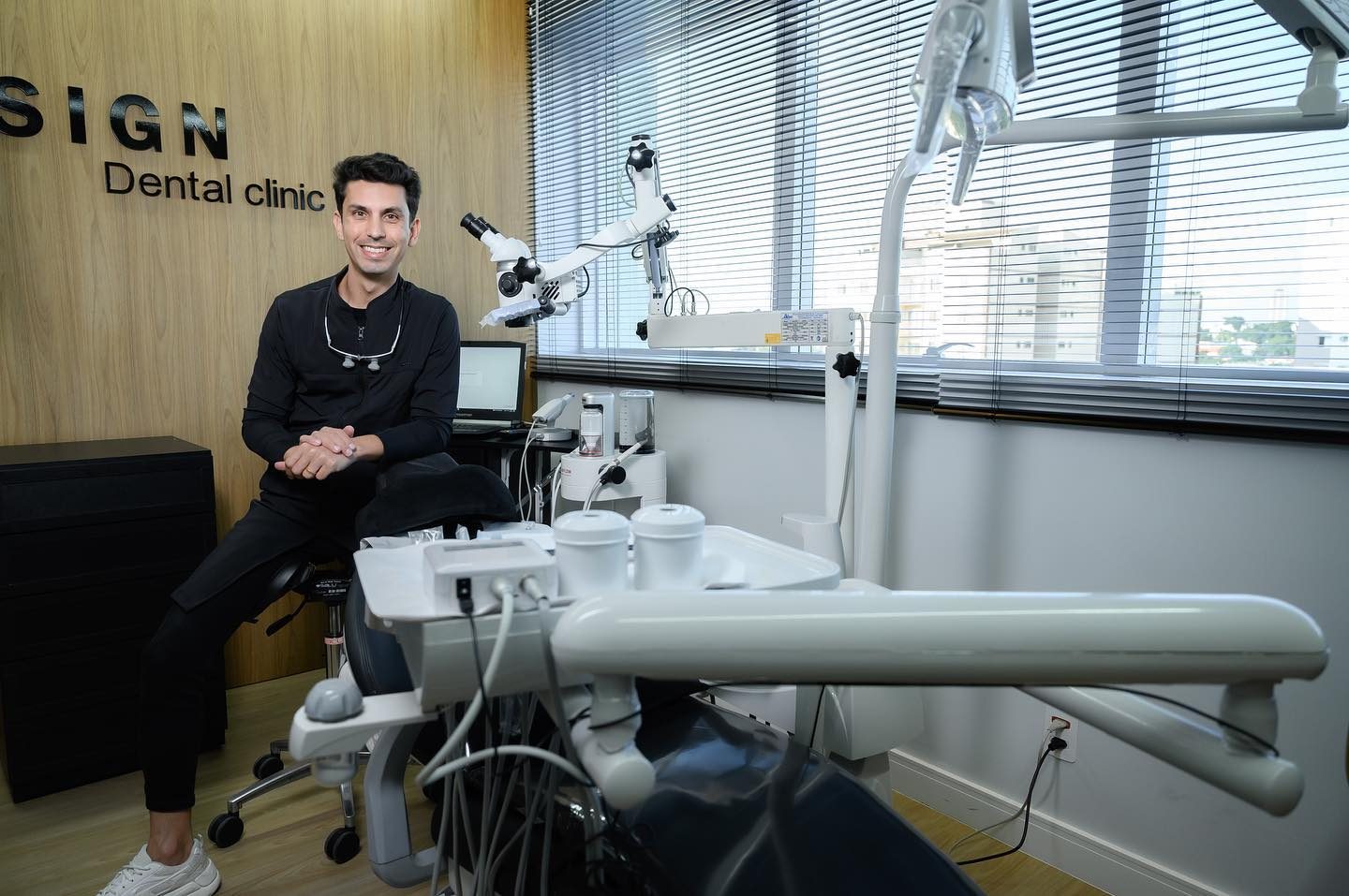 Dr. Felipe Giani no consultório da clínica, ao lado do microscópio