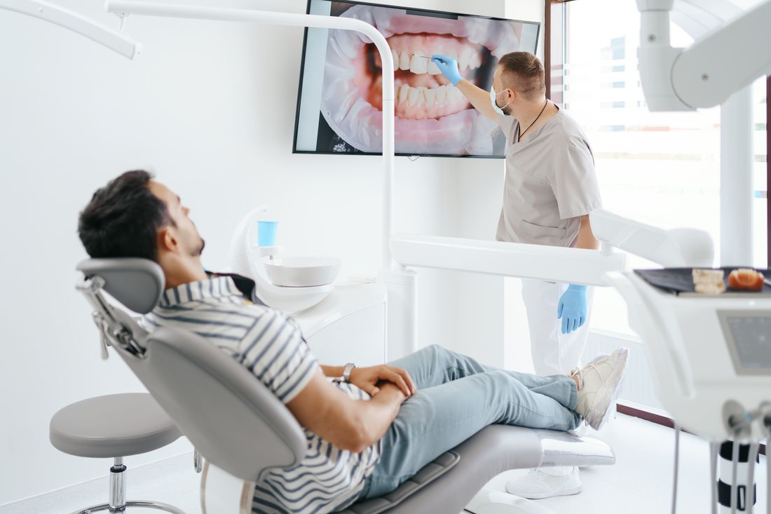 Dentista mostrando ao paciente a imagem dos dentes em um monitor